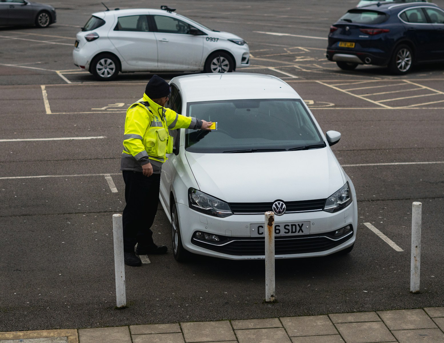 man in yellow jacket standing beside white car auto